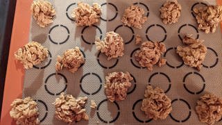 Schmackhafte Haferflocken-Plätzchen, die zur Adventszeit mit Lebkuchengewürz verfeinert werden können. Die Haferflocken-Plätzchen liegen auf einer Backmatte.