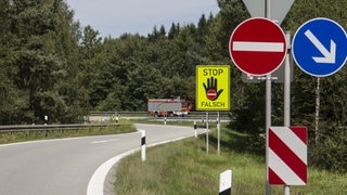 Grelgelbe Warntafeln mit schwarzer Hand und Stoppschild warnen an einer Autobahnausfahrt davor, sie als Auffahrt zu benutzen