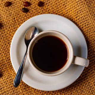 Tasse mit schwarzem Kaffee, dekoriert mit Kaffeebohnen