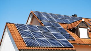Viele Solarpanel bilden auf einem Gebäudedach eine Photovoltaikanlage, die Solarstrom aus Sonnenenergie erzeugt.