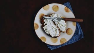 Ein Teller mit zwei geschmierten Scheiben Brot mit Frischkäse