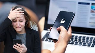 Junge Frau blickt verzweifelt auf ihr Handy. Neue Phishing-Masche: Betrüger geben sich als Bankmitarbeiter aus.