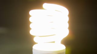 Eine Energiesparlampe leuchtet mit 60 Watt vor einem dunklen Hintergrund.