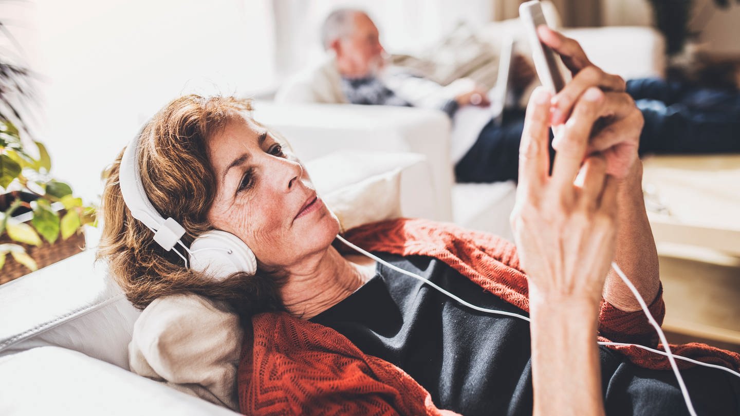 Digitales Erbe, digitaler Nachlass: Frau liegt mit Smartphone auf dem Sofa.