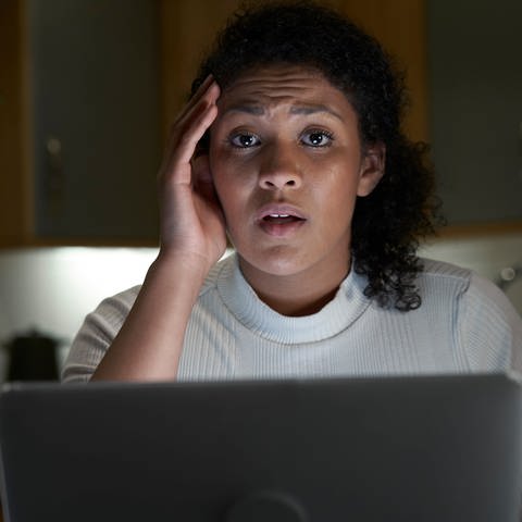 Eine Frau schaut geschockt auf ihren Laptop. Kriminelle tarnen sich bei Amazon oder Ebay als seriöser Shop und zocken Kunden ab. Opfer haben zudem Mühe, nicht selbst als Betrüger dazustehen. 