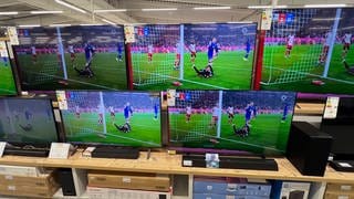 Neue TV-Geräte stehen in einem Erektronik-Markt und zeigen Szenen eines Fußballspiels.