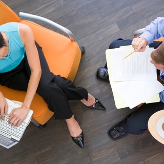 Mann und Frau arbeiten im Büro mit Laptop und Papier.