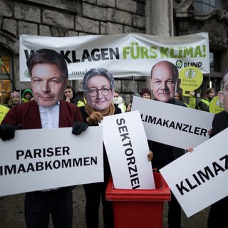 Eine Protestaktion von Deutscher Umwelthilfe und BUND bei der Teilnehmer Masken mit Bildern von Politikern tragen 