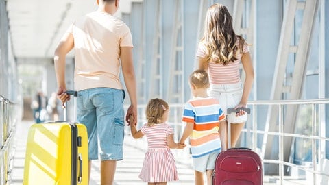 Eine Familie mit Koffern läuft am Flughafen entlang. Die schönsten Wochen im Jahr – aber oft gibt es Ärger im Urlaub, mit Flug, Hotel, den Preisen. Wie kommen Reisende zu ihrem Recht? Tipps vom Rechtsexperten. 