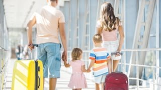 Eine Familie mit Koffern läuft am Flughafen entlang. Die schönsten Wochen im Jahr – aber oft gibt es Ärger im Urlaub, mit Flug, Hotel, den Preisen. Wie kommen Reisende zu ihrem Recht? Tipps vom Rechtsexperten. 