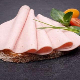 Lyoner-Scheiben liegen auf einem Butterbrot. Schinkenwurst im Test von Kaufland, Rewe, Aldi, Edeka: Welche Lioner schmeckt gut?