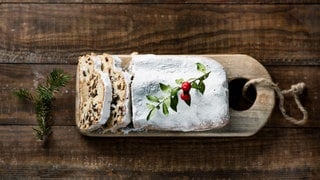 Christstollen liegt auf einem Holzbrett. Hier ein original Dresdner Rezept. 