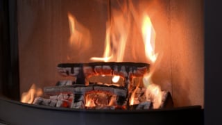 Brennende Holzbalken in einem Kamin: Das Feuer schlägt hohe Flammen.