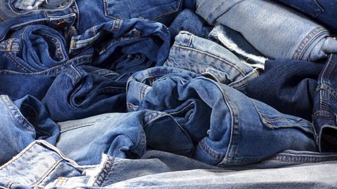 Die Nahaufnahme zeigt einen Haufen Jeans in verschiedenen blau Tönen. Nachhaltige Mode: so geht Jeans ohne Chemie in der Herstellung.