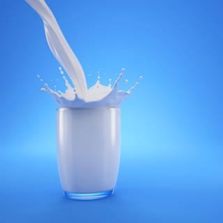 Milch wird in ein Trinkglas geschüttet