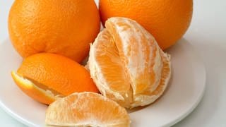 Orangen,Orangenschalen und geschälte Orangen liegen auf einem Teller