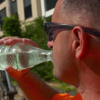 ein Straßenbauer trinkt aus einer Wasserflasche