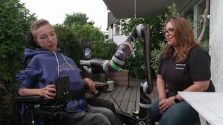 Junge mit Behinderung bedient einen Roboter-Greifarm